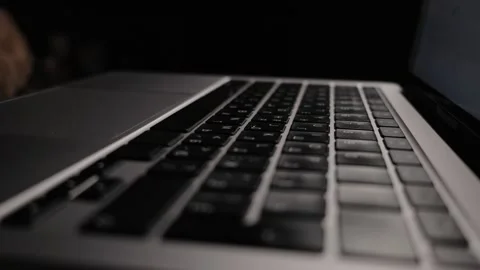Close-up low angle shot of a modern laptop keyboard and trackpad in a dark Stock Footage 339174520