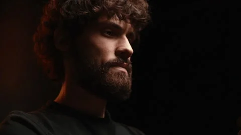 Close-up of low-angle shot of serious young man looking away in dark room Stock Footage 146543462