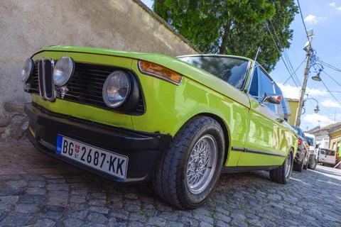 Close-up low-angle view of a bright green vintage car parked on a cobblestone Stock Photos