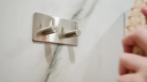 Close low-angle view of chrome double hook on veined marble wall, revealing Stock Footage 345656218
