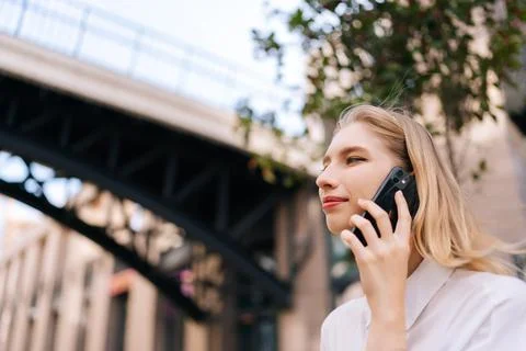 Close-up low-angle view face of attractive blonde lady talking on mobile phone Stock Photos