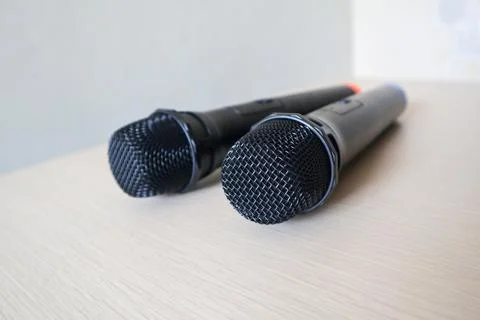 Close-up low angle view of two black handheld wireless microphones resting .. Stock Photos