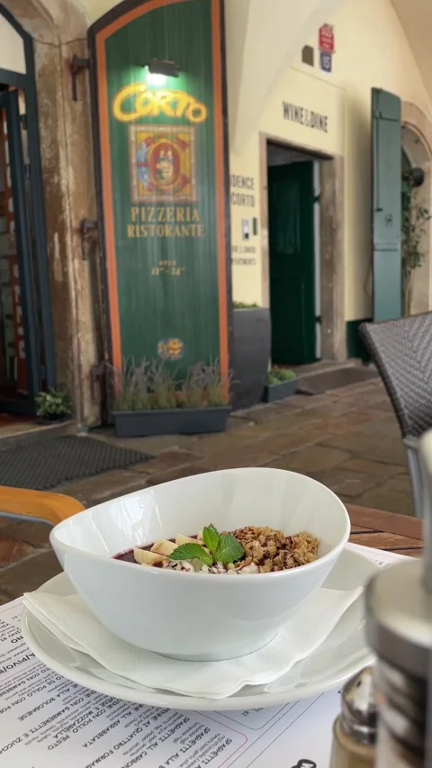 Close low table shot of granola bowl at outdoor pizzeria entrance with Видео 344585022