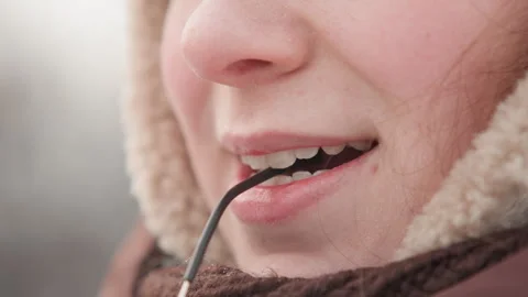 Close-up lower face biting eyeglass temple, fur-lined hood and knitted scarf Stock Footage 345652422