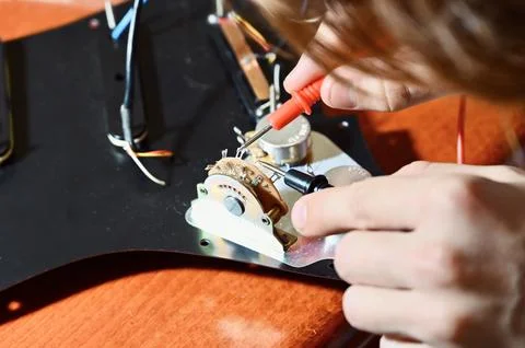 Close-up of a luthier testing electric guitar wiring with a multimeter Stock Photos