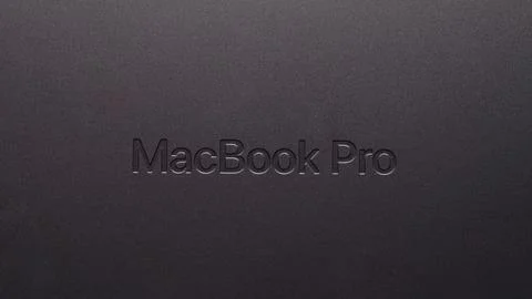 Close-up of a MacBook Pro logo engraved on Space Black metallic surface. Stock Photos