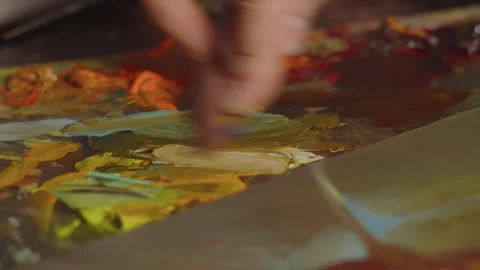 Close-up, macro, the artist's hand mixes oil paints for a painting on a table in Stock Footage 247563841