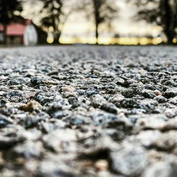 Close-up macro asphalt road texture in an orange summer evening sunset. Stock Photos