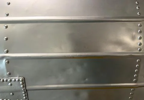 Close-up macro of bright silver colored metal wall with lines of bolts Stock Photos
