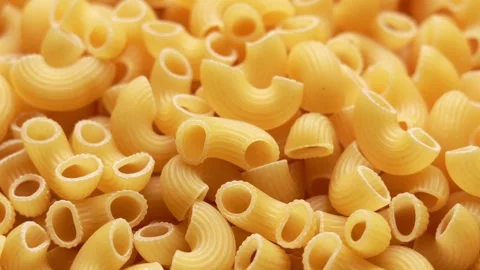 Close up macro of dry uncooked elbow macaroni pasta showing ridged golden Stock-Footage 347459142