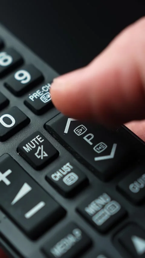 Close-up macro of a finger using a TV remote’s channel program rocker and Stock Footage 332246432