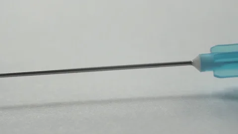 Close-up macro footage of a sharp sterile medical needle on a syringe on a white Stock Footage 127467571