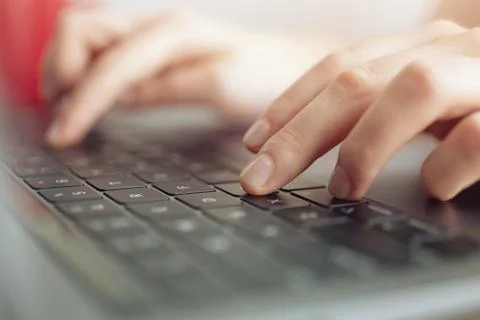 Close up macro of hands typing on black laptop computer keyboard Stock Photos
