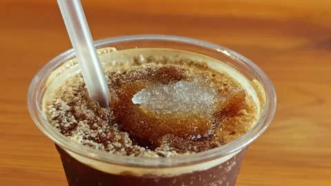 Close-up macro of iced black coffee with crushed ice on a wooden table. Stock Footage 348157383