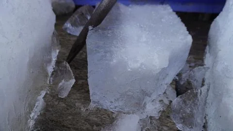 Close-up macro of large clear ice cubes with frosty surface, black utensil. Stock Photos