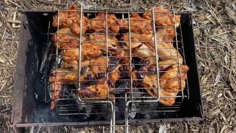 Close-up macro shot of chicken wings being grilled on a charcoal barbecue grill Stock Footage 237465675