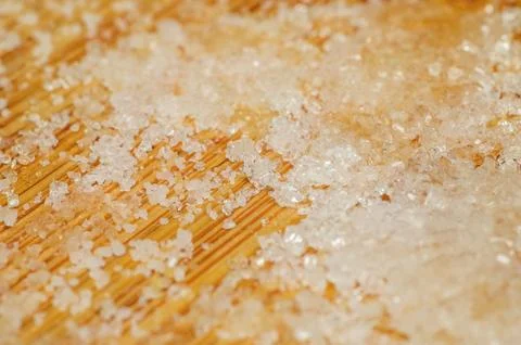 Close up macro shot of coarse sugar crystals scattered on a wooden surface Fotos de archivo