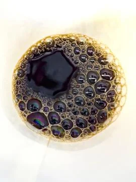 Close-up macro shot of coffee bubbles forming a foam layer. The iridescent re Stock Photos