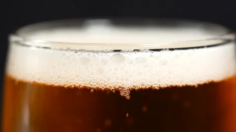A close-up macro shot of a freshly poured beer in a glass with frothy foam Stock Footage 314793604