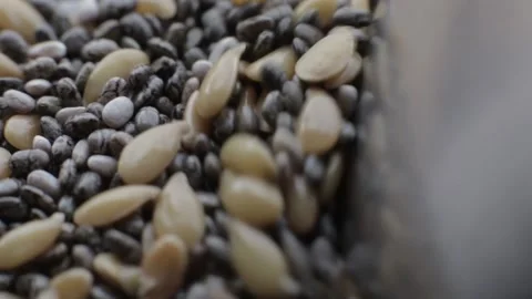 Close-up macro shot of linseed and shia seeds being mixtured on a stainless stee Stock Footage 205518855