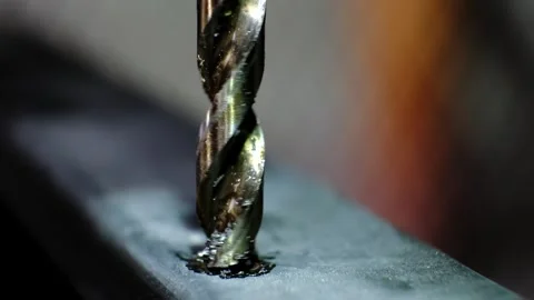 Close-up macro shot of a metallic twisting drill bit drilling a dark metallic Stock Footage 338087708