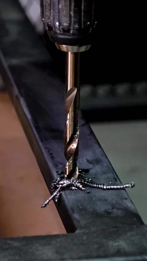 Close-up macro shot of a metallic twisting drill bit drilling a dark metallic Stock Footage 338402317