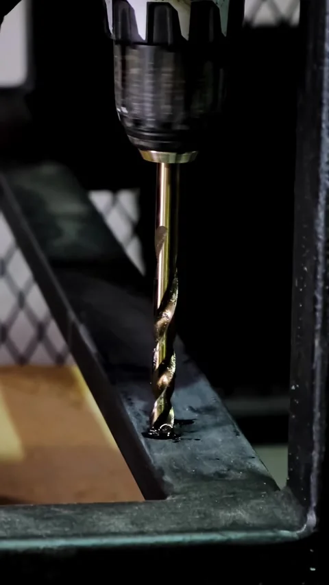 Close-up macro shot of a metallic twisting drill bit drilling a dark metallic Stock Footage 338402329
