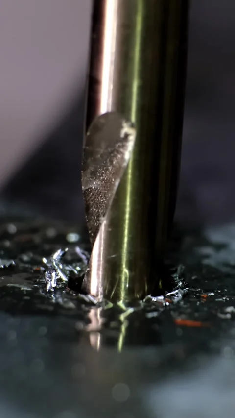 Close-up macro shot of a metallic twisting drill bit drilling a dark metallic Stock Footage 338402377