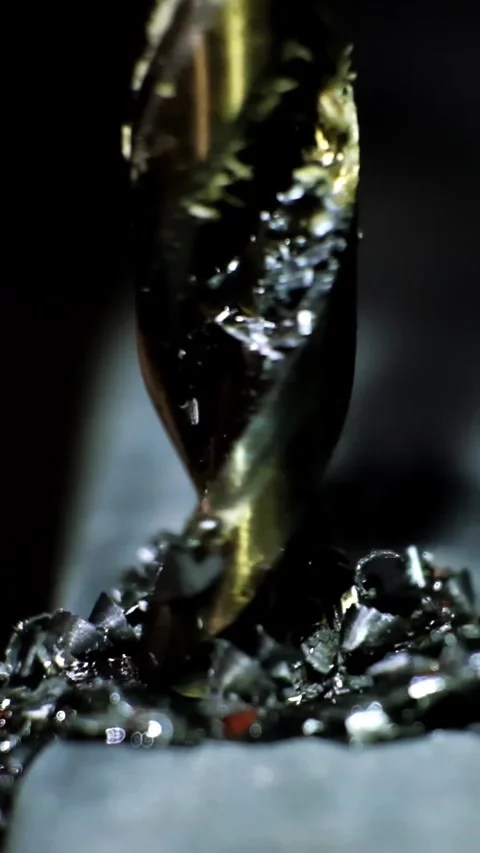 Close-up macro shot of a metallic twisting drill bit drilling a dark metallic Stock Footage 338402474