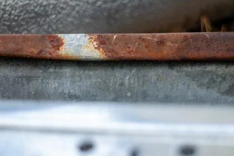 Close-up macro shot of old rusted metal edge against textured galvanized stee Stock Photos