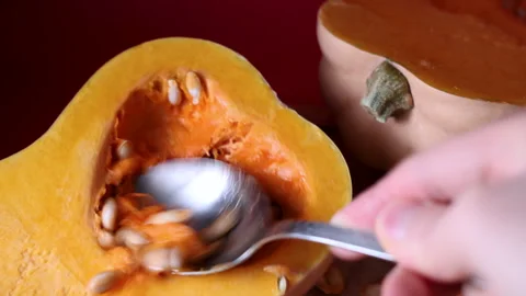 Close-up macro shot of a person removing seeds from a halved butternut squa.. Stock Footage 319786029