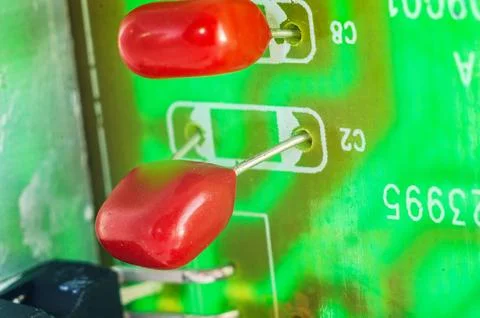 Close-up macro shot of red ceramic capacitors on a green circuit board with.. Stock Photos
