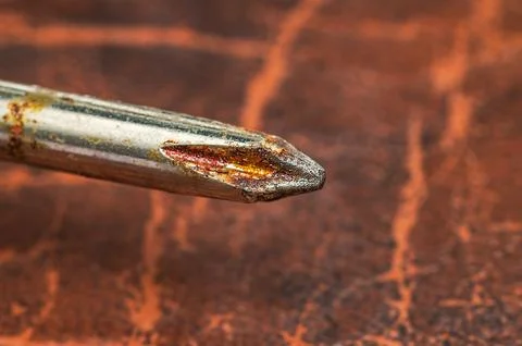 Close-up macro shot of a rusty Phillips head screwdriver tip on a textured .. Stock Photos