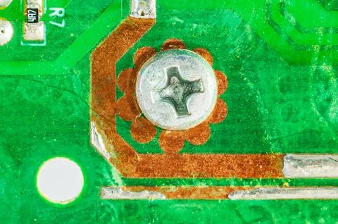Close-up macro shot of a screw securing a circuit board with copper traces Foto stock