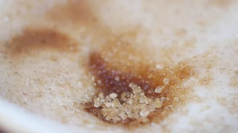 Close up macro shot of sugar crystals dissolving in rich frothy coffee. Vídeos de archivo 333157486