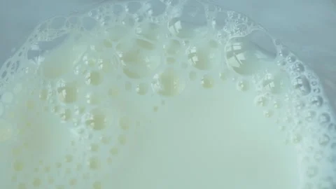 Close up macro shot of white milk with many small bubbles rising and popping. Stock Footage 332407229