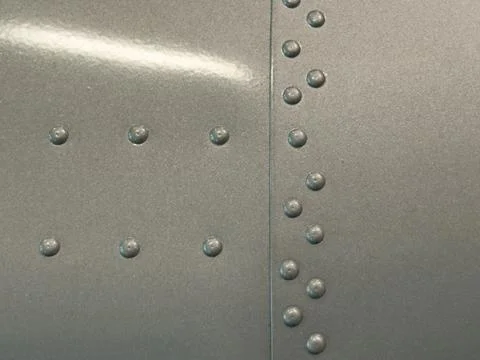 Close-up macro of silver colored metal machine with lines of rivets Stock Photos