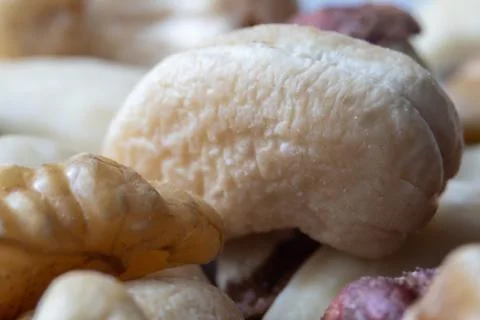 Close-up macro of a single cashew nut among mixed nuts, highlighting textur.. Stock Photos