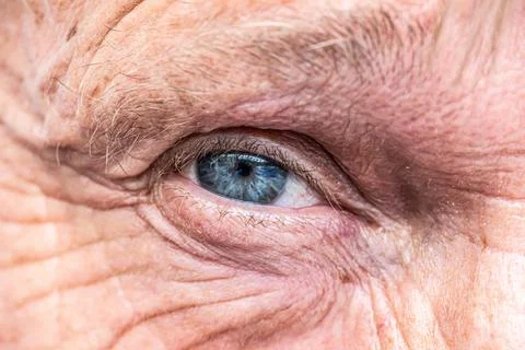 Close-up macro view on the blue eye of senior man smiling Stock Photos