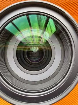 Close-up macro view of a camera lens aperture with reflections of green bui.. Stockfoto's