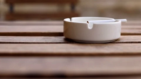 Close-up macro view of cigarette in white ashtray on wooden table on blur backgr Vídeos de archivo 118506484