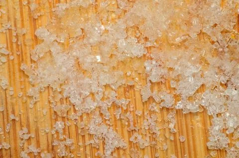 Close-up macro view of coarse sugar crystals scattered on a wooden surface Стоковые фото
