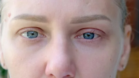 Close-up of macro zoom shot of sad wet blue eyes. Young beautiful blonde looks 動画素材 210156986