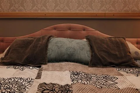 Close-up of a made bed with a decorative blue pillow and brown cushions against Stock Photos