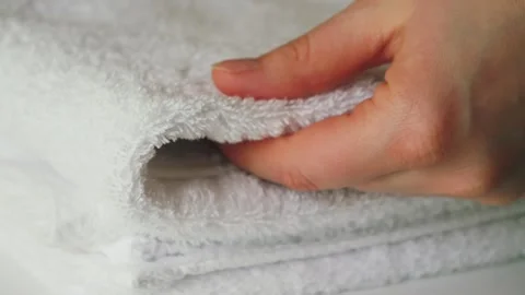 A close-up of a maids hand folding and smoothing white towels. The scene Stock Footage 334134440