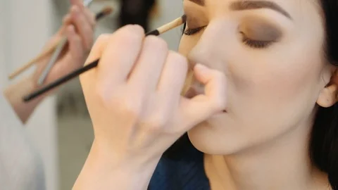 Close-up of a make-up artist applying make-up to the eyelash Видео 73646887
