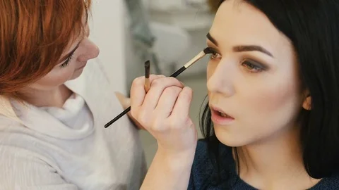 Close-up of a make-up artist applying make-up to the eyelash Видео 73780679