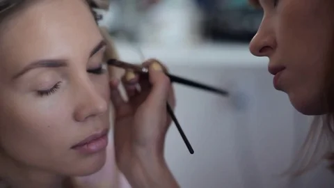 Close-up. Make-up artist does make-up on the clauses of a girl in a beauty salon Stock Footage 83844760