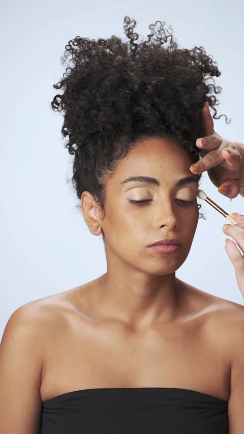 Close-up makeup application on young curly-haired model in studio Stock Footage 340053672