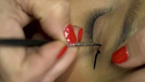 Close-up of a Makeup Artist's Hands with Red Fingernails Painting Model's Eyes Stock Footage 128388503